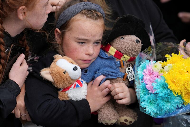 A young girl holds Paddington Bear and Corgi stuffed toys while waiting to watch the procession of Queen Elizabeth's coffin from the Palace of Holyroodhouse to the Royal Mile in Edinburgh. Reuters