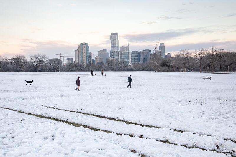 People walk their dogs through the snow at Zilker Park in Austin, Texas, U.S., on Thursday, Feb. 18, 2021. Texas is restricting the flow of natural gas across state lines in an extraordinary move that some are calling a violation of the U.S. Constitutions commerce clause. Photographer: Thomas Ryan Allison/Bloomberg