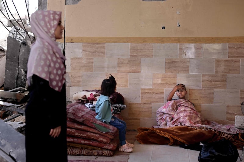 A Palestinian family collect bedding from their damaged home as they prepare to move into a school run by the United Nations Relief and Works Agency for Palestine Refugees in Gaza city. AFP