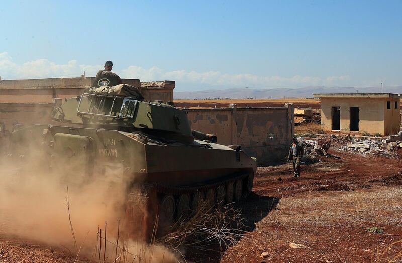 TOPSHOT - A Syrian government tank drives next to a building near the town of Khan Shaykhun in the southern countryside of the rebel-held Idlib province on August 18, 2019. A Turkish military convoy crossed into jihadist-run northwest Syria on August 19, it's path blocked by advancing regime troops as tensions soared between Damascus and Ankara, which said its forces were targeted by an air strike. / AFP / -
