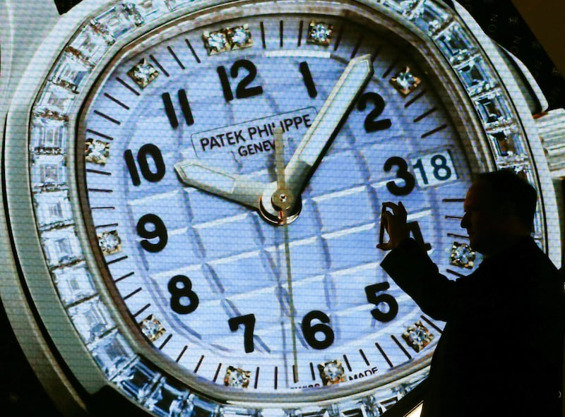 A visitor takes pictures in front of a display of Swiss watch manufacturer Patek Philippe at the Baselworld Watch and Jewellery Show in Basel, Switzerland March 23, 2017. REUTERS/Arnd Wiegmann - RTX32FQC