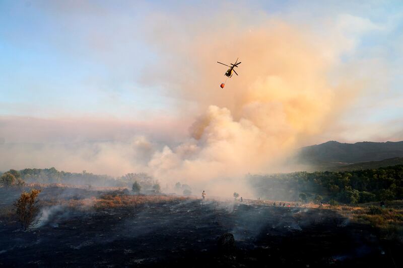 A helicopter makes a water drop as a wildfire burns in the village of Navalmoral, Spain.