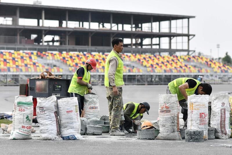 (FILES) In this file photo taken on February 14, 2020, workers set up a kerb on the track at the under-construction Formula One Vietnam Grand Prix race track site in Hanoi, amid concerns of the COVID-19 coronavirus outbreak. Vietnam's inaugural F1 Grand Prix will take place in Hanoi as planned, organisers told AFP on February 18, bucking a trend of cancellations as fears over the COVID-19 coronavirus rip up Asia's sporting calendar. / AFP / Manan VATSYAYANA
