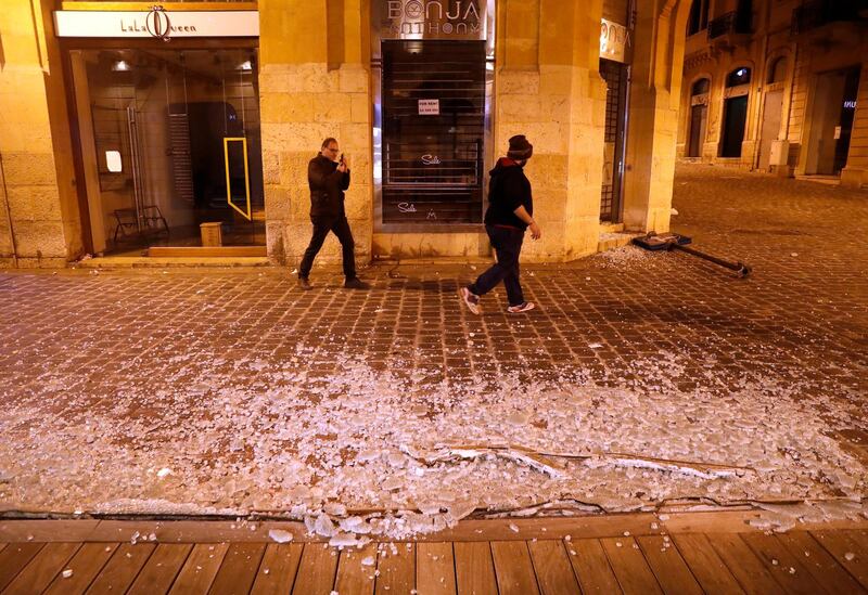 Men pass in front of a coffee shop that was smashed by anti-government protesters. AP Photo
