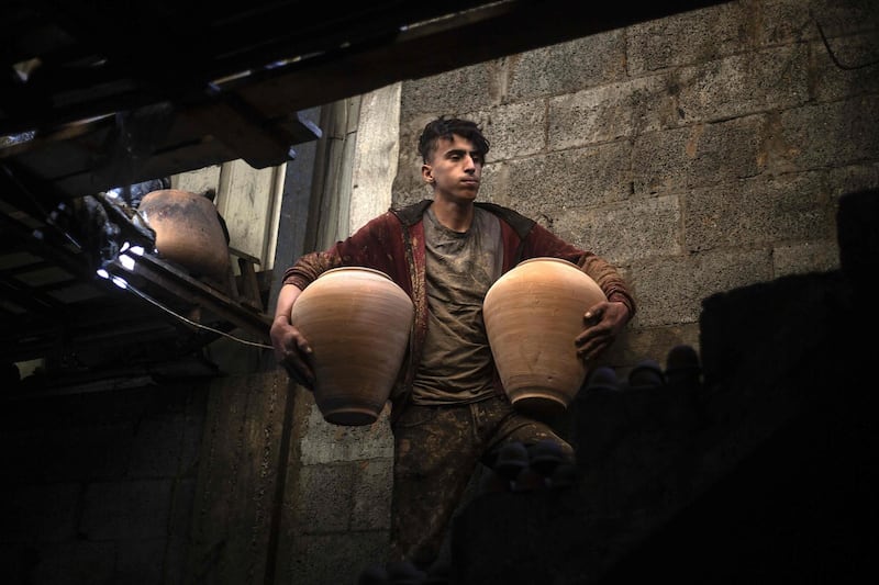 A son of Palestinian potter Sid Atallah carries dry clay pots at the family workshop in the central Gaza Strip. AFP