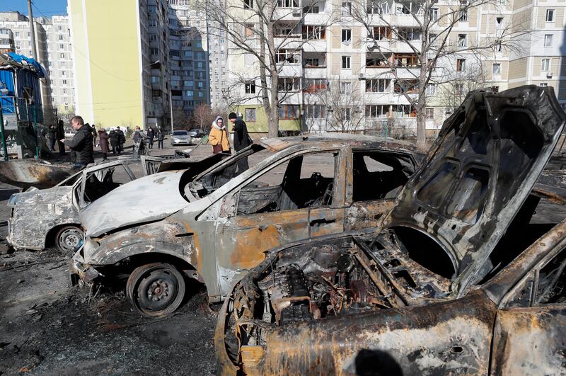 People walk past burnt cars on Monday after the shelling of a residential area in Kiev, Ukraine. EPA