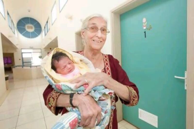 Young at heart: Wilhelmina van de Weg holds a baby at Fujairah Maternity Hospital.