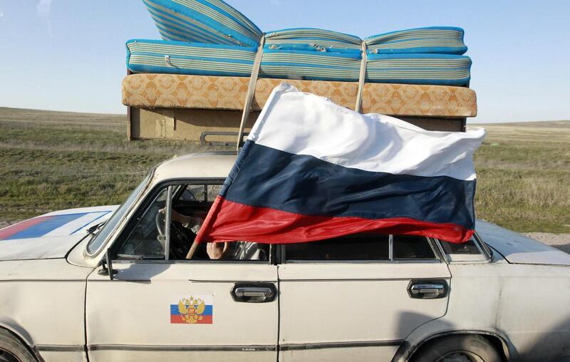 A car drives with a Russian flag on a road outside the Crimean port city of Feodosia. Shamil Zhumatov / Reuters