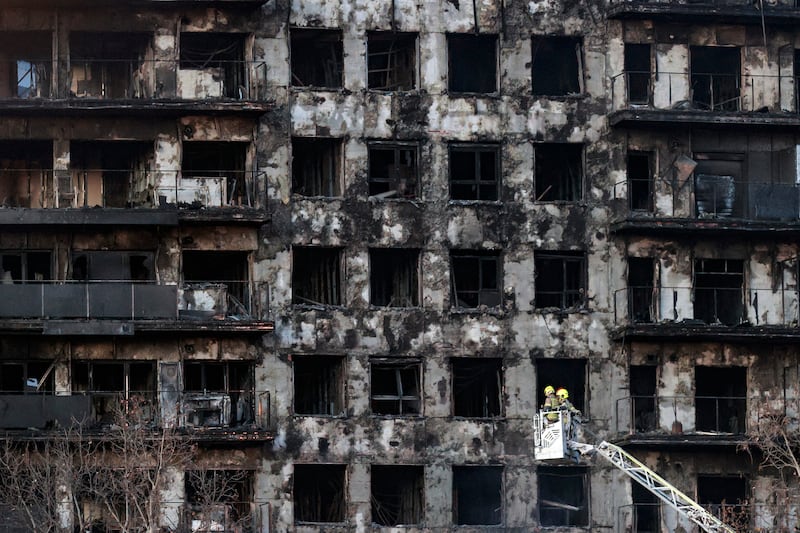 Firefighters check the facade of a building after a fire, in Valencia, Spain. A fire broke out in a residential building on February 22, leaving four dead and 19 missing. EPA