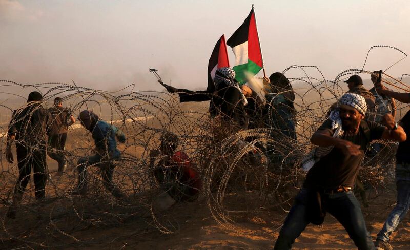 A protester uses a sling shot to hurls stones while others throw stones near the fence of the Gaza Strip border with Israel, during the protest. AP Photo