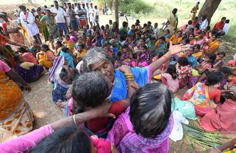 Indian women mourn the death of relatives in a case of food poisoning at Bidarahalli, near Sulawadi village in Chamarajnagar district of Karnataka state, India, Saturday, Dec. 15, 2018. Police on Saturday arrested three people after at least 10 died of suspected food poisoning following a ceremony to celebrate the construction of a new Hindu temple in southern India. (AP Photo/Madhusudhan Sr)