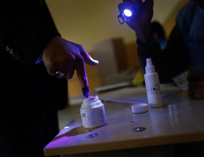 An election official uses an infrared light to check the thumb of a voter as the man dips his finger in ink before voting at a polling station in Kabul April 5, 2014. Voting began on Saturday in Afghanistan’s presidential election, which will mark the first democratic transfer of power since the country was tipped into chaos by the fall of the hardline Islamist Taliban regime in 2001. Tim Wimborne / Reuters