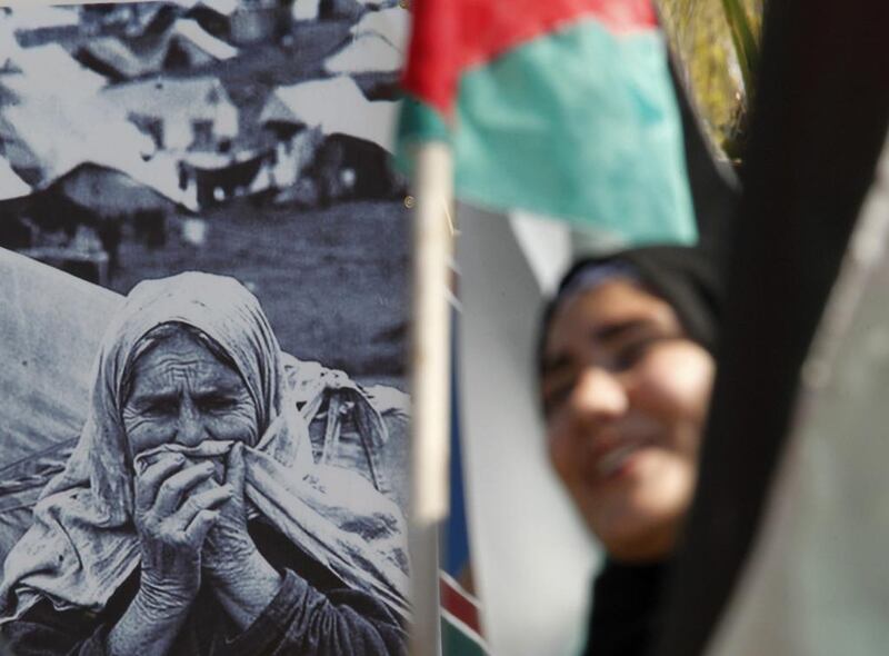 A Palestinian woman holds a Palestinian flag as she stands in front of a picture during a march to mark the 66th anniversary of Nakba in Sidon, as they make their way to the town of Naqoura, in southern Lebanon near the border between Lebanon and Israel. Ali Hashisho / Reuters