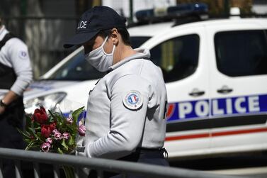 A police officer holds flowers brought by people to the scene of the attack in Rambouillet, south-west of French capital Paris. AFP