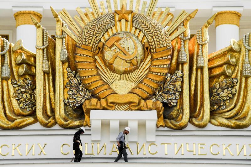 Workers fix a cornice close to Soviet Union state emblem atop the Central Pavilion at the All-Russia Exhibition Centre (VDNKh), a trade show and amusement park in Moscow.  AFP