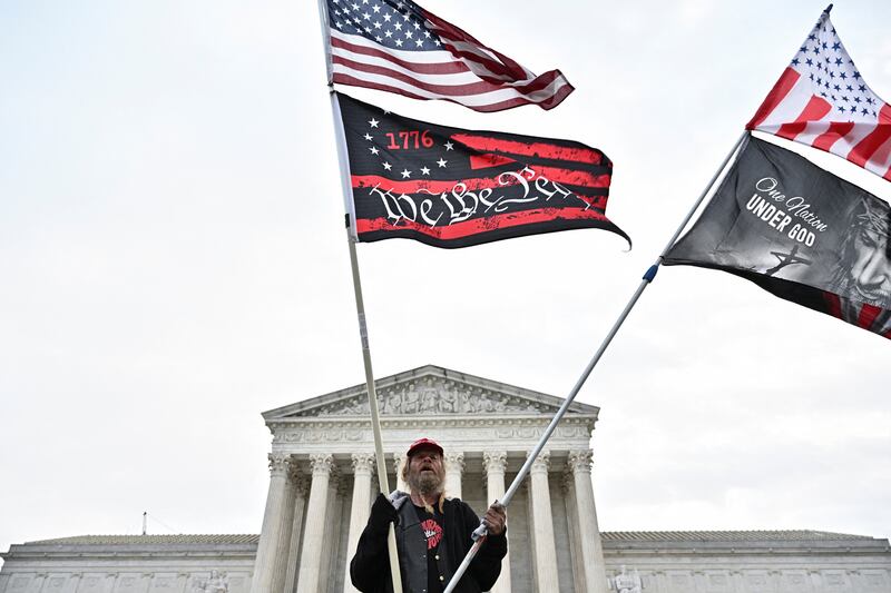 A man waves American and protest flags in front of the US  Supreme Court. Reuters