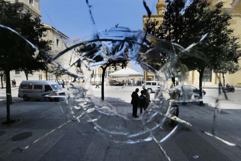 Lebanese are seen through hole in the glass window of a store damaged in clashes between protesters and police officers, a day after a violent protest against the ongoing trash crisis, in downtown Beirut on August 24, 2015. Hassan Ammar / AP Photo