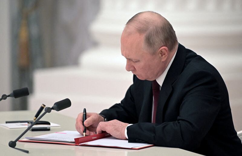Mr Putin signs documents, including the decree recognising two Russian-backed breakaway regions in eastern Ukraine. Reuters