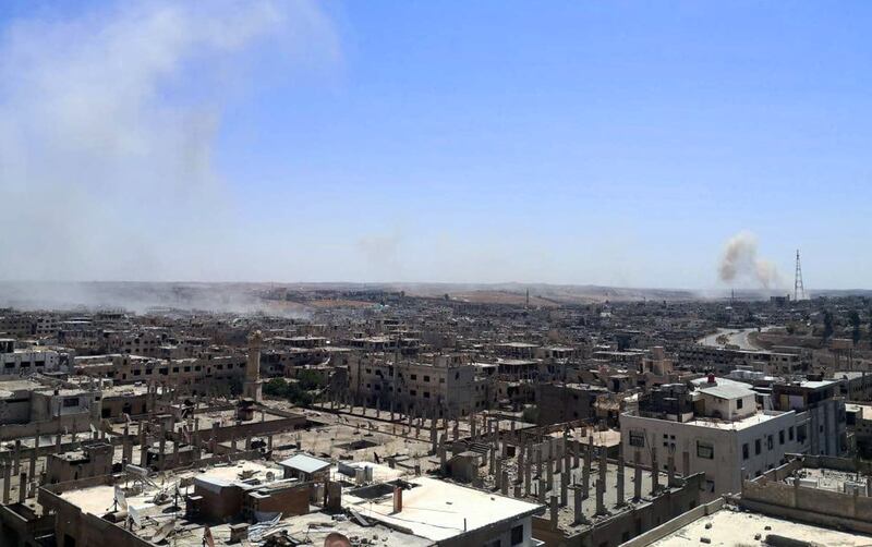 Smoke rises over damaged buildings in the opposition-held southern Syrian enclave of Deraa, in this handout released by Sana on August 31, 2021. Reuters