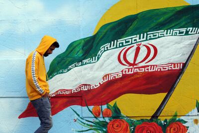 epa08003481 An Iranian walks next a wall painting of Iranian national flag, Tehran, Iran, 17 November 2019. According to reports, internet access has been limited in the country amid protests over increasing fuel price in Iran.  EPA/ABEDIN TAHERKENAREH