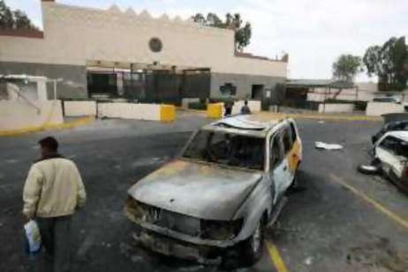 A man inspects damaged vehicles in front of the main entrance of the U.S. Embassy, in background, in San'a, Yemen, Thursday, Sept. 18, 2008. Yemen's foreign minister says the attack on the U.S. embassy has the markings of al-Qaida, but investigators are still determining who was behind the deadly assault. (AP Photo/Nasser Nasser) *** Local Caption ***  NN101_Mideast_Yemen_US_Embassy.jpg