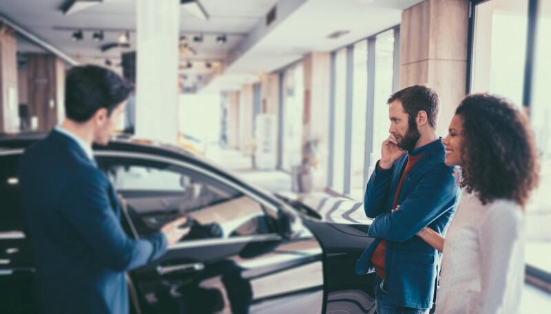 Young woman and her husband in the showroom purchasing new car. Getty Images