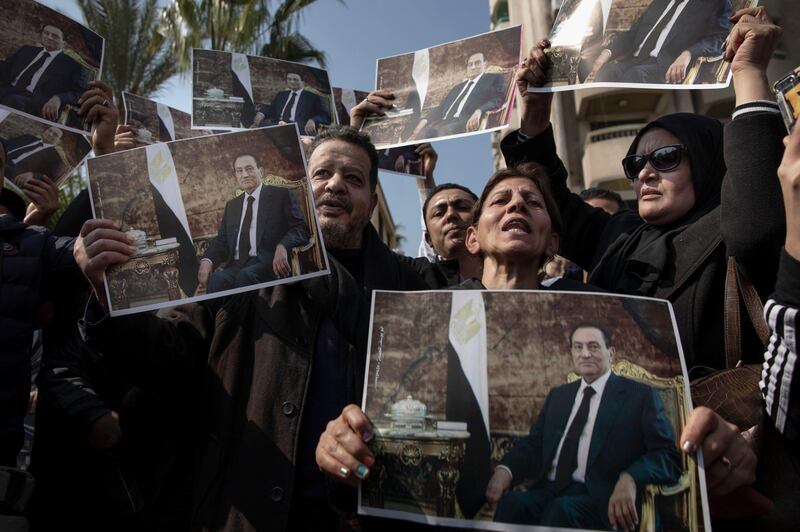 Supporters of ousted President Hosni Mubarak hold posters with his photograph near the cemetery where he will be buried. AP Photo