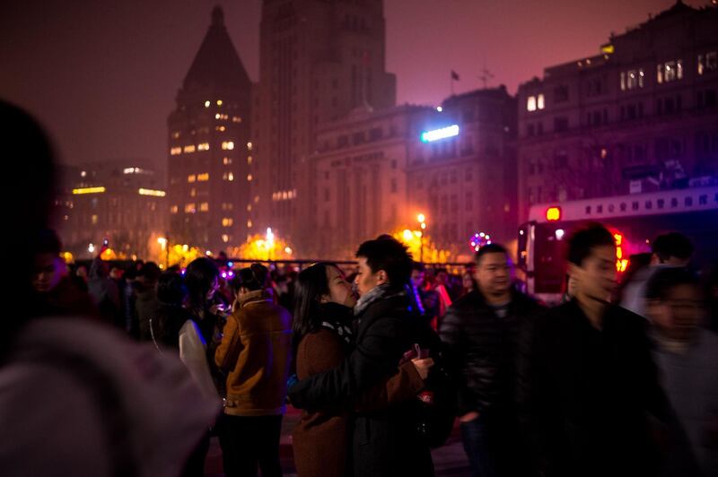 A couple kisses as people gather on the Bund along the Huangpu River during New Year celebrations in Shanghai at the start of January 1, 2018.  / AFP PHOTO / CHANDAN KHANNA