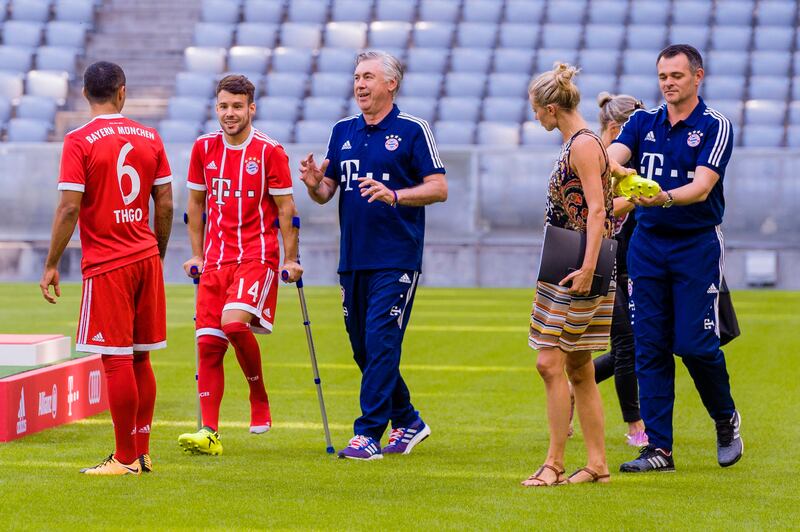 and Bayern Munich's Italian head coach Carlo Ancelotti (C) and Bayern Munich's Spanish midfielder Juan Bernat hobbels on crutches to the team photo session of FC Bayern Munich in the southern German city of Munich on August 8, 2017. / AFP PHOTO / Guenter SCHIFFMANN