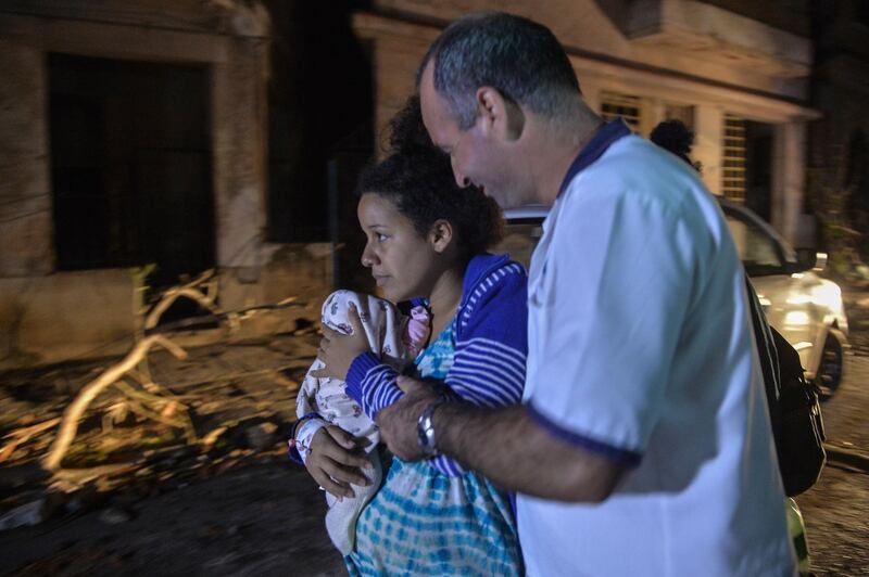 A Cuban paramedic assists a mother and her baby during evacuations in the tornado-hit Luyano neighbourhood in Havana early on January 28, 2019.&nbsp;AFP
