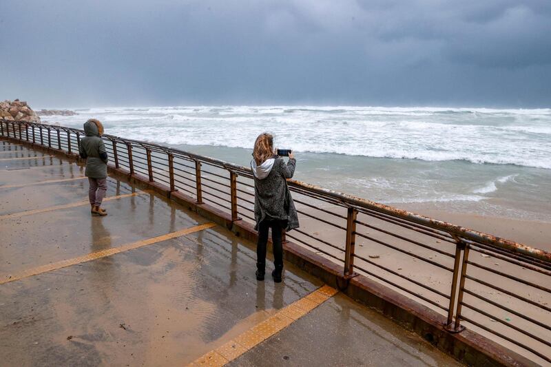 A woman uses her phone to take photos of the storm along the Mediterranean coast in the Israeli city of Netanya. AFP