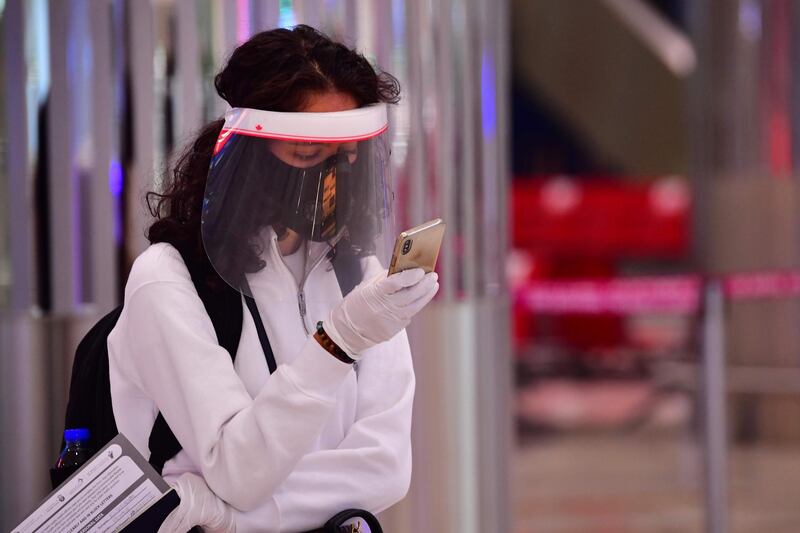 A tourist checks her phone as she waits for medical screening. AFP