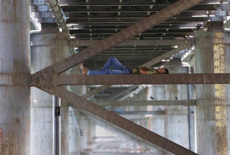 A man rests on a steel cantilever, supporting a bridge, on river Sabarmati in a hot day in Ahmadabad.  Ajit Solanki / AP Photo