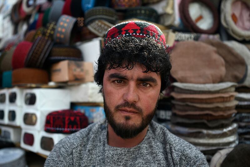 In this photo taken on March 1, 2022, an Afghan hat vendor wearing an Uzbek cap waits for customers at his stall in a market near the Pul-e Khishti Mosque in Kabul.  - At the crossroads of central and south Asia, Afghanistan has for centuries been a meeting place for cultures and ethnicities, leaving its mark in the striking assortment of headgear worn by its people.  The style of a cap or turban confers status and standing on its wearer, and also signifies what part of the country they come from or which ethnic group they belong to.  (Photo by Wakil KOHSAR  /  AFP)  /  TO GO WITH 'Afghanistan-culture-hats'