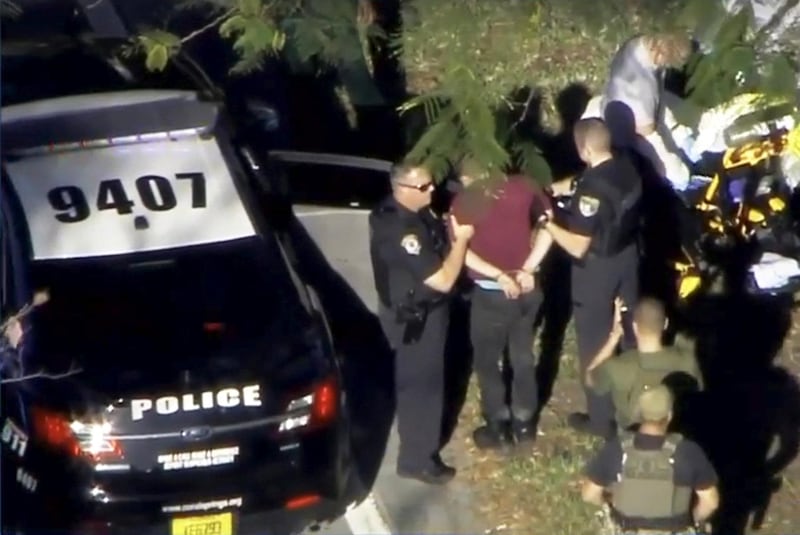 A man placed in handcuffs is led by police near Marjory Stoneman Douglas High School following a shooting incident in Parkland, Florida, U.S. February 14, 2018 in a still image from video. WSVN.com via REUTERS. ATTENTION EDITORS - THIS IMAGES HAS BEEN PROVIDED BY A THIRD PARTY. NO RESALES, NO ARCHIVES. MANDATORY CREDIT. NO ACCESS SOUTHEAST FLORIDA MEDIA.