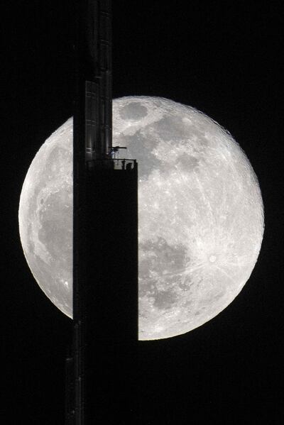 A photo taken on April 27, 2021 shows the April's full moon, known as the Super Pink Moon, behind the Burj Khalifa in Dubai. / AFP / GIUSEPPE CACACE
