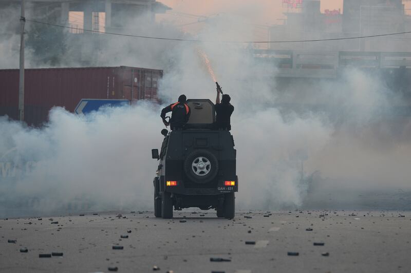 Officers fire tear gas shells to disperse supporters of Mr Khan, in Islamabad. AP