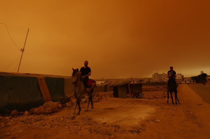 Syrians ride horses during a dust storm on the outskirts of the rebel-held town of Dana, in the north-western Idlib province, near the Turkish border.