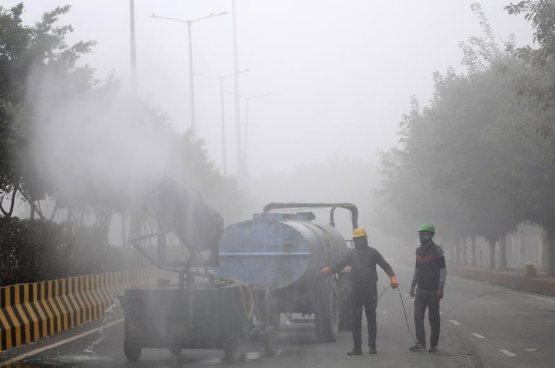NOIDA, INDIA  JANUARY 24: Workers spraying water on a road to curb pollution in Sector 96, on January 24, 2021 in Noida, India. (Photo by Sunil Ghosh/Hindustan Times via Getty Images)