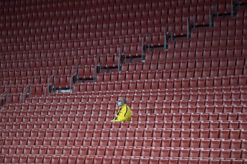 A stadium worker wearing a face mask sits in the empty stands. AFP