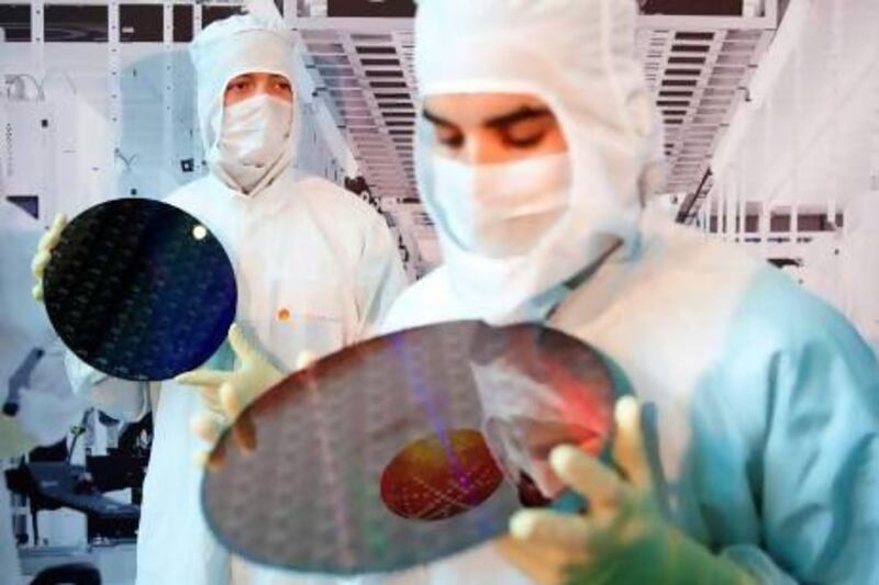 GlobalFoundries employees hold 300mm wafers at the company's plant in Dresden, Germany. The industry is heading towards 14 nanometre chips, expected to be in production by next year. Oliver Killig / AFP