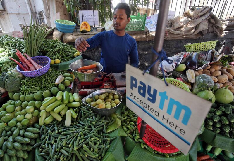 A vendor weighs vegetable next to an advertisement of Paytm, a digital payments firm, hanging amidst his vegetables at a roadside market in Mumbai, India, April 2, 2019. REUTERS/Francis Mascarenhas