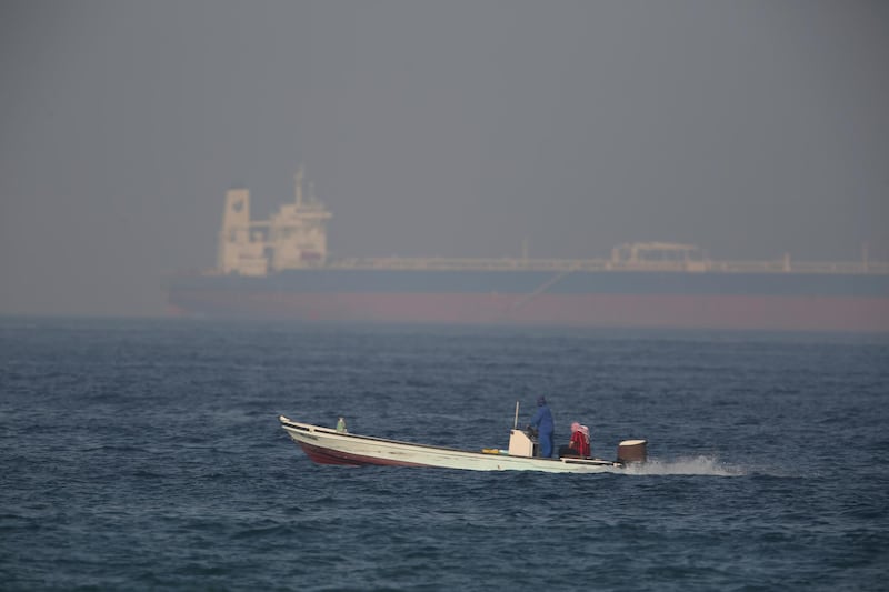 A fishing boat speeds past an oil tanker in the distance in Fujairah, UAE. AP Photo