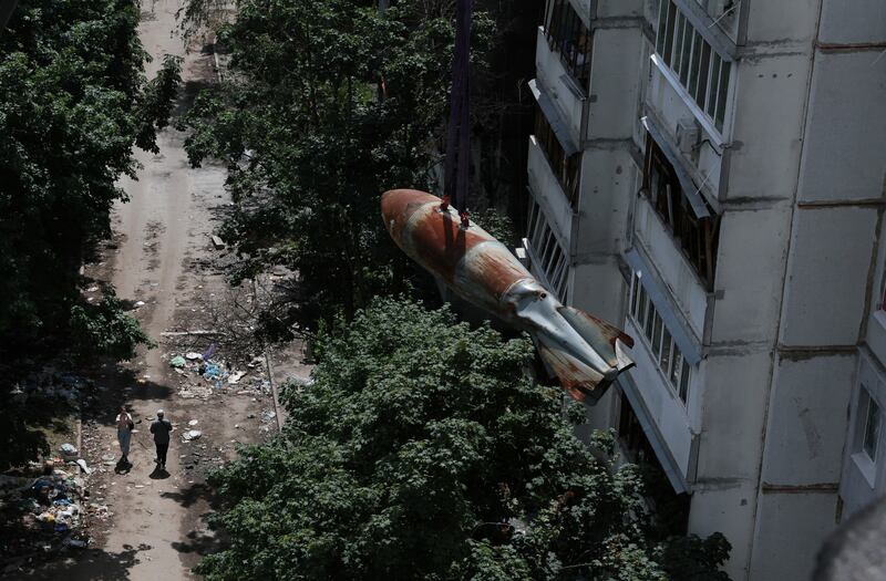 People watch as a defused 500kg bomb that did not detonate when it landed on an apartment building in March is lowered from the roof, in Kharkiv, Ukraine. Reuters