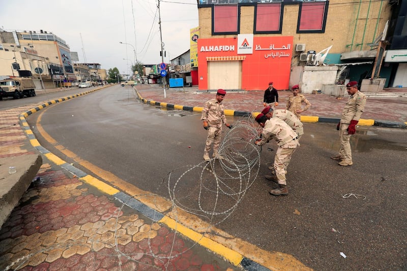 Soldiers place barbed wire on a street during a curfew in Baghdad. Reuters