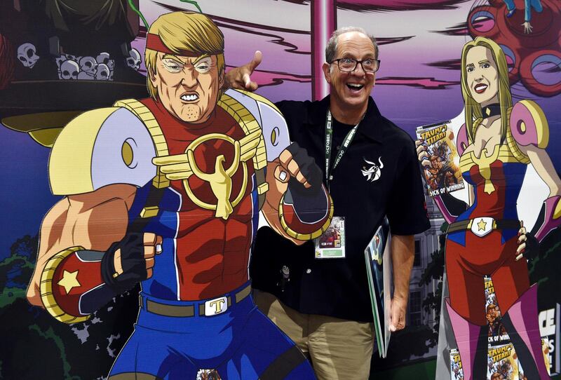 Paul Nestor, of San Diego, poses next to cut-out figures of President Donald Trump and his daughter Ivanka at a booth for the satirical comic book series "Trump's Titans" during Preview Night. AP Photo