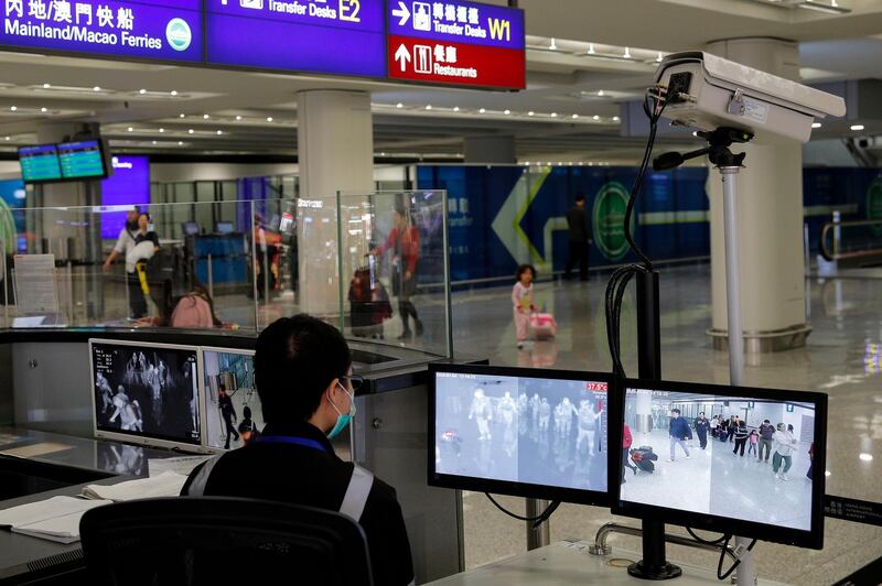 FILE - In this Jan. 4, 2020, file photo, a health surveillance officer monitors passengers arriving at the Hong Kong International airport in Hong Kong. A preliminary investigation into viral pneumonia illnesses sickening dozens of people in and around China has identified the possible cause as a new type of coronavirus, state media said Thursday, Jan. 9, 2020. In Hong Kong, 15 patients with symptoms of respiratory illness were being treated as of Sunday. (AP Photo/Andy Wong, File)