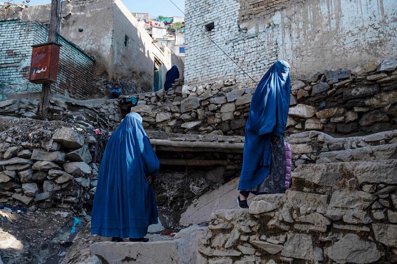 Burqa-clad Afghan women climb a stony path in Kabul. AFP