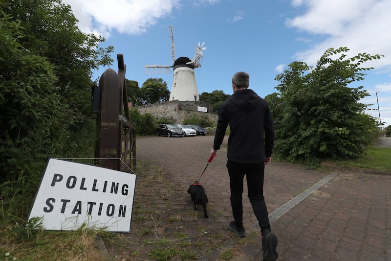 A man and his dog walk towards Falwell windmill and mill which is a temporary polling station in Sunderland. AP