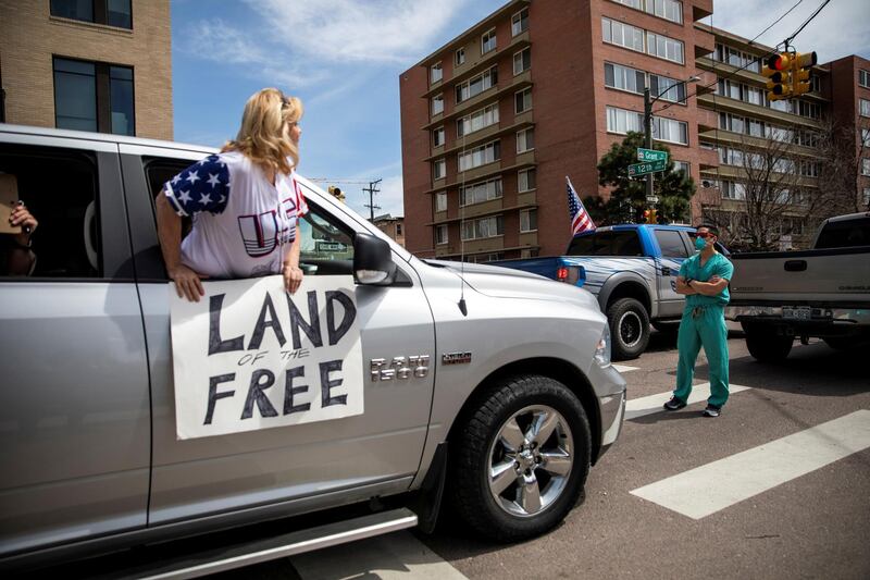 Healthcare workers stand in the street in counter-protest to hundreds of people who gathered at the State Capitol to demand the stay-at-home order be lifted in Denver, Colorado, US. Reuters